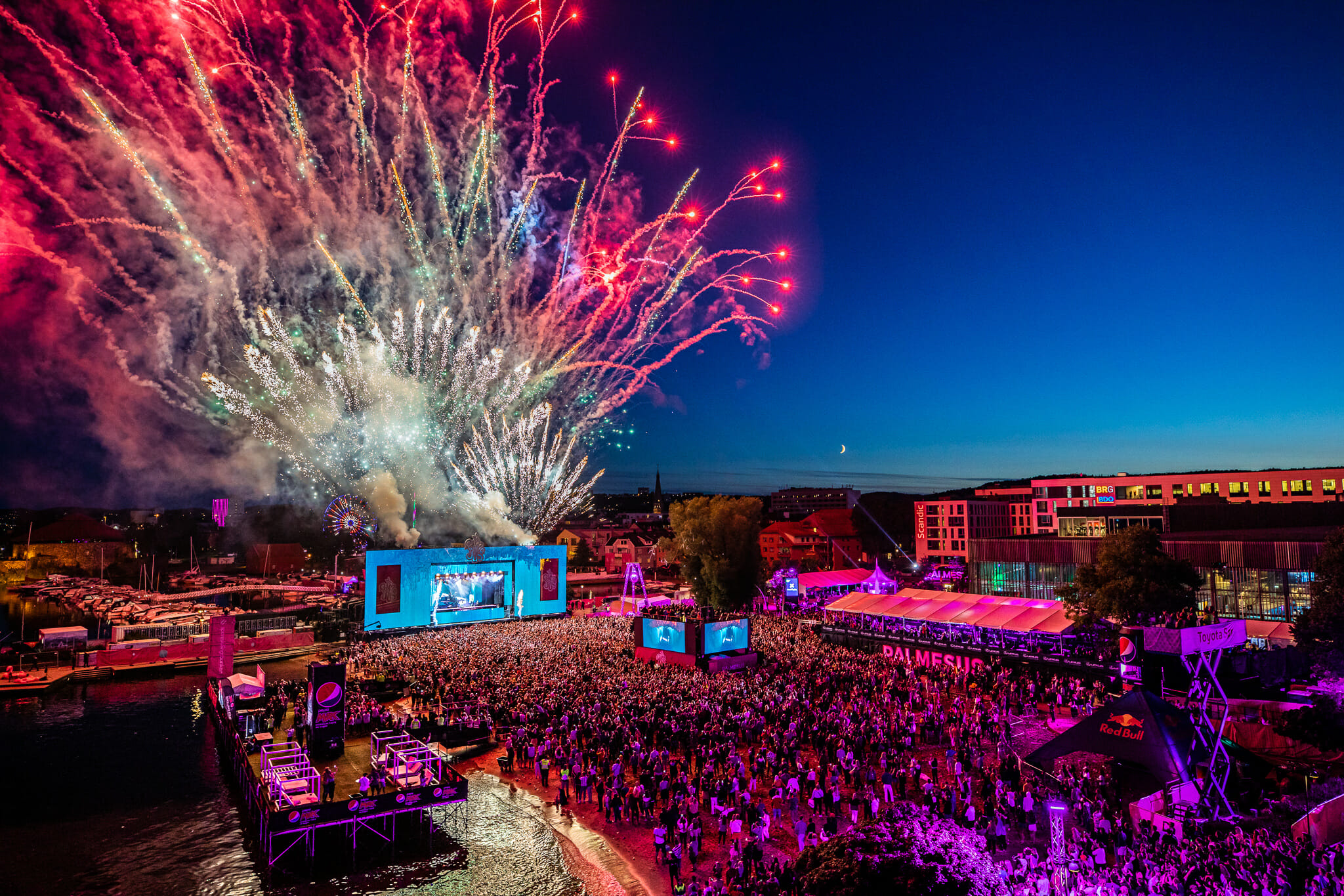 Bildet viser hele festivalområdet til Palmesus 2022. Det er fullt blant publikum og over hovedscenen er det et massivt fyrverkeri. Bildet er tatt på kvelden.